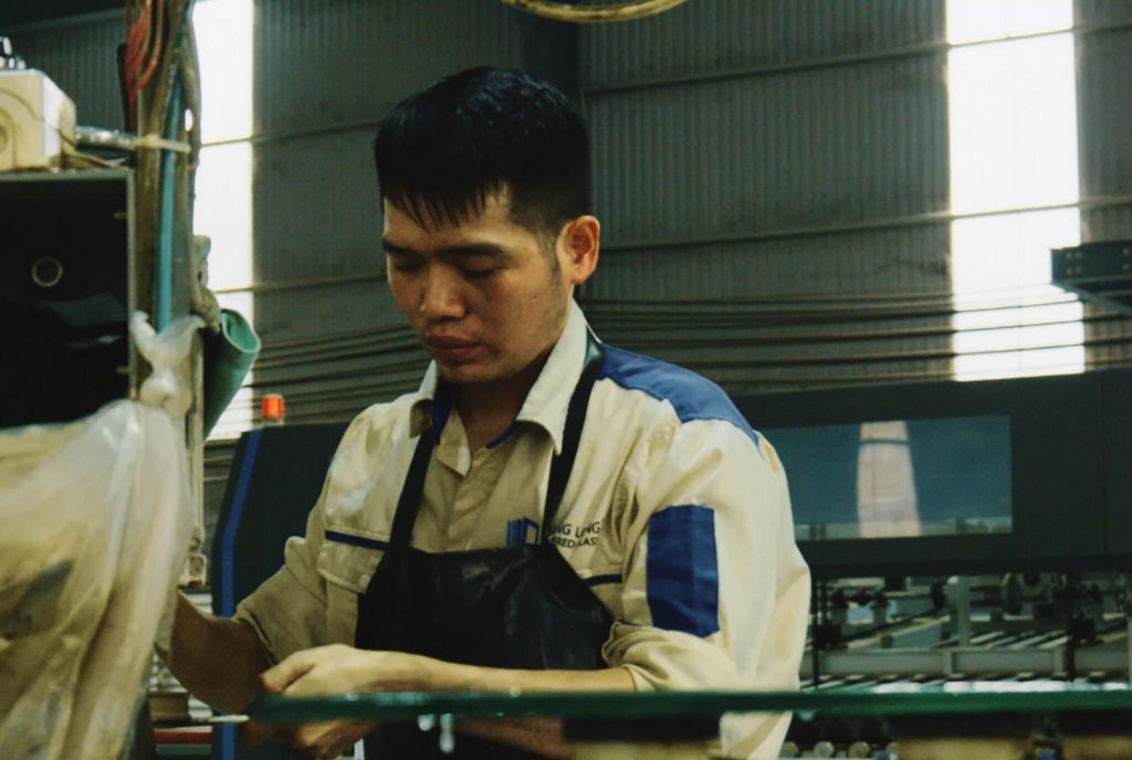 Thợ gia công Thăng Long Glass đang thao tác trên máy mài cạnh kính hiện đại tại xưởng.